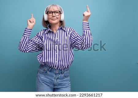 bright cheerful middle-aged woman with gray hair with headphones without wire on a bright studio background