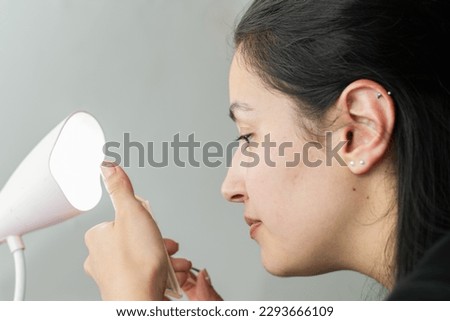 profile view of a beautiful latina woman looking at herself in the mirror, ready to start applying makeup