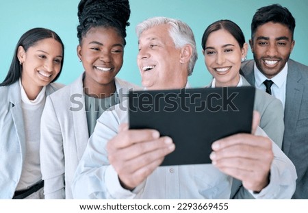Thats an awesome picture. Studio shot of a diverse group of corporate businesspeople using a tablet to take selfies against a blue background.