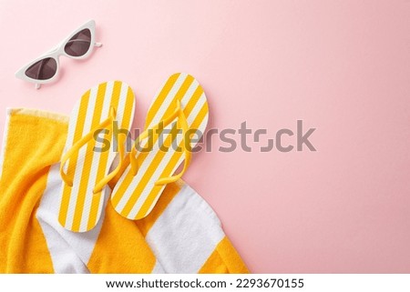 Top view of summer accessories concept. Flat lay of yellow striped flip-flops, towel, vintage sunglasses on pastel pink background with empty space for text or advert Royalty-Free Stock Photo #2293670155