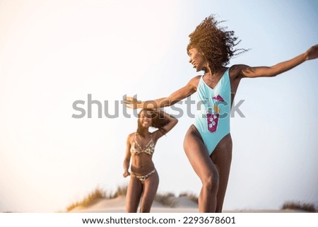 Laughing women playing running having fun on beach