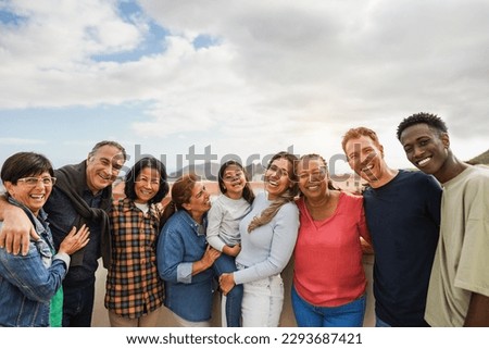 Group of multigenerational friends smiling in front of camera - Multiracial friends of different ages having fun together - Main focus on center people faces Royalty-Free Stock Photo #2293687421