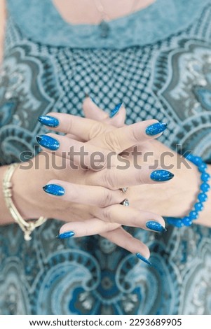 Woman's beautiful hand with long nails and blue manicure