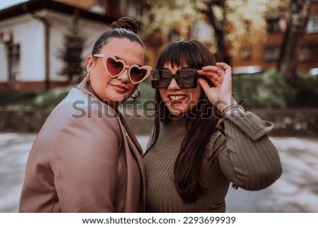 Two young women embrace each other emotionally outside on a sunny day while wearing sunglasses Royalty-Free Stock Photo #2293699939
