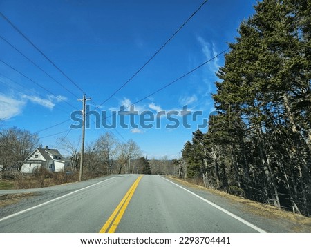 An open highway with vegetation along it on a clear spring day.