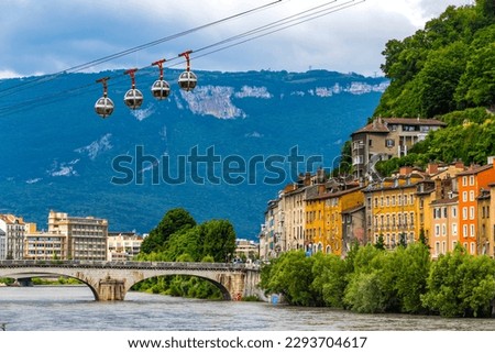 Isere river in Grenoble city skyline, Auvergne-Rhone-Alpes region, France. Pont Marius-Gontard bridge, Grenoble-Bastille Cable car (Telepherique) and Alps mountains on background Royalty-Free Stock Photo #2293704617