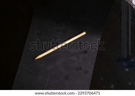 Wooden textured large black graphite pencil used for writing taken in studio on a black background ZUVJSUX
