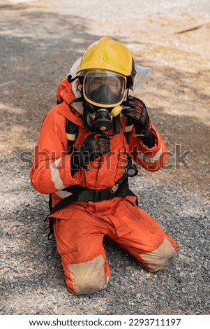 Vertical picture of a firefighter sits on his knees taking off his helmet.