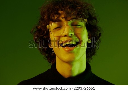 Man portrait close-up portrait in glasses fashion and style emotion, hipster teen lifestyle, portrait green background mixed neon light, copy space