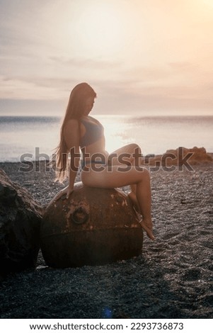 Woman summer travel sea. A happy tourist enjoys taking pictures of her travels, posing by an old, rusty sea mine on a beach surrounded by volcanic mountains, sharing travel adventure journey
