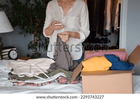 Woman is taking a picture of her unwanted clothing items to resale online