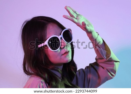 The young adult Asian woman with casual clothes in the neon lightning studio photography.