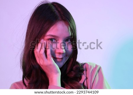 The young adult Asian woman with casual clothes in the neon lightning studio photography.