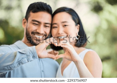 With you, my heart is whole. Shot of a happy young couple making a heart shaped gesture in a garden.