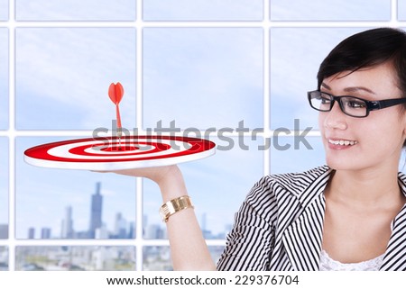 Beautiful asian businesswoman holding a target at modern office