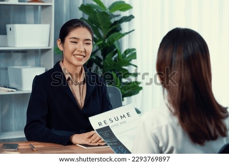 Two asian women conduct job interview in office. Applicants wear formal suit while talking about her CV and job application. Interviewer ask inquiry in positive and conversational manner. Enthusiastic Royalty-Free Stock Photo #2293769897