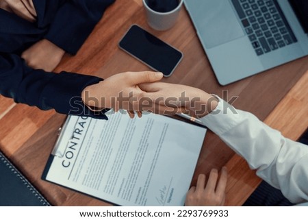 Two professionals successfully close business deal with closeup handshake, sealing the partnership agreement. Legal document and signature as formal agreement between the two companies. Enthusiastic
