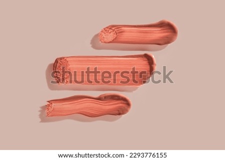 Three strokes of lip gloss on a beige background. Royalty-Free Stock Photo #2293776155