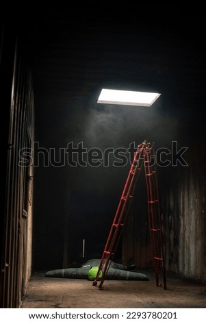 Vertical picture of red ladder is set in a tin room where a dummy victim is lying in the galvanized room with soft light.