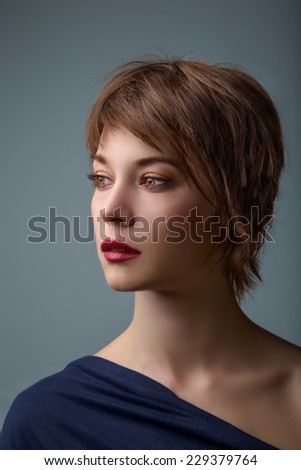 Side portrait of a young woman with short brown hair and brown glowing eyes. Royalty-Free Stock Photo #229379764