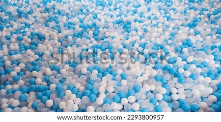 Blue and white plastic balls in ball pool at kids playground. Colorful plastic ball texture background. Many small colorful hollow plastic soft kids balls are in a ball pit. Play toy for kids.