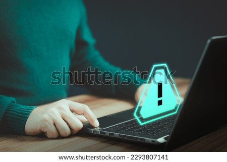 Man working on computer laptop with triangle caution warning sign for notification error and maintenance. Technology concept of computer virus detected, personal data protection, network security.