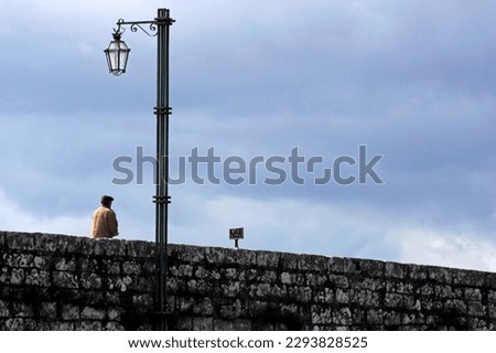 Man crossing the old bridge of medieval city of Ponte de Lima in the north of Portugal
