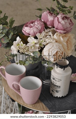two pink mugs on the table, a bouquet of flowers, a peony on the table