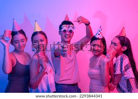 Five party goers being carefree and having a great time. 5 young people on a plain background lit with pink and blue lights.