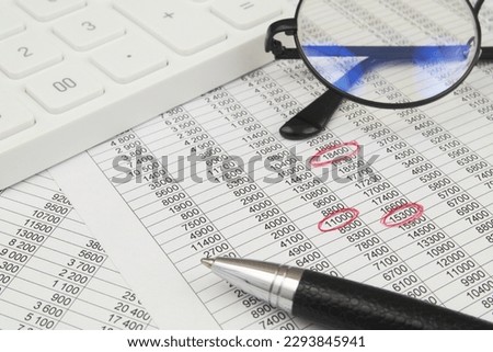 Financial data analytics and finding mistakes concept. White calculator, pen and eyeglasses on documents with marks. Royalty-Free Stock Photo #2293845941