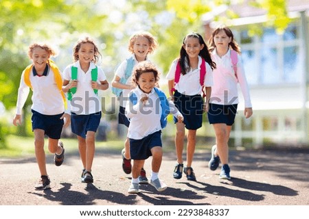 Kids go back to school. Interracial group of children of mixed age run and cheer on the first day of new academic year. Start of school holiday. Preschooler or kindergarten kid. Child in school yard. Royalty-Free Stock Photo #2293848337