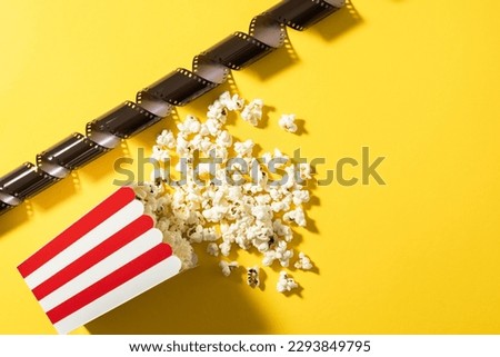 Popcorn and film stock on yellow background