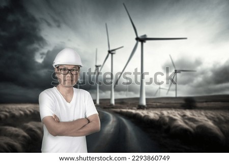 Male engineer arm crossed at wind turbine power generator station.
