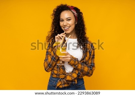 Young woman with cocktail on yellow background