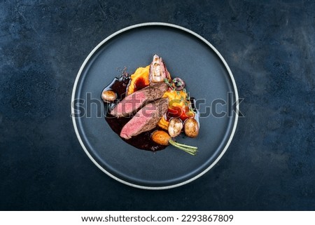 Modern style traditional wild hare back filet braised with wild berries and red wine jus with mashed carrot puree and sweet potato served as top view on Nordic design plate with copy space  Royalty-Free Stock Photo #2293867809