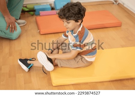 Kid putting on shoes in kindergarten 