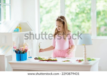 Child creating picture with colorful leaves. Art and crafts for kids. Little girl making collage image with rainbow plant leaf. Biology homework for young school student. Creative autumn home fun.