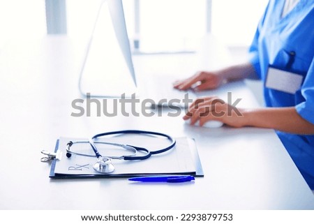 Female doctor sitting on the desk and working a laptop in hospital.