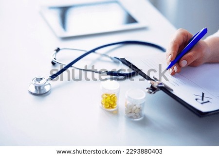A woman holding a pill bottle of white and a written treatment plan on the table.