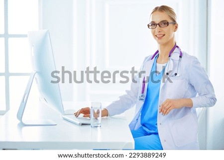 Portrait of young female doctor sitting at desk in hospital.