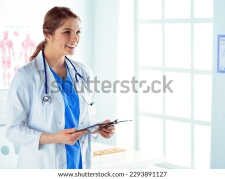 Smiling female doctor with a folder in uniform standing.