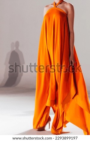 Fashion model woman wearing bright long orange yellow summer dress. Casual stylish female clothes concept. Fashion week catwalk fashion details