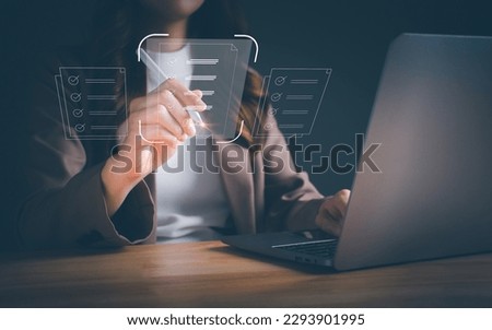 Businesswoman working on laptop with electronics document icons, using a stylus pen checking list on a digital tablet. electronic signature, signing, E-document management paperless workplace concept