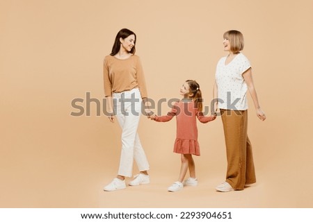 Full body side view happy fun cool women wear casual clothes with child kid girl 6-7 years old. Granny mother daughter walk holding hands isolated on plain beige background. Family parent day concept Royalty-Free Stock Photo #2293904651