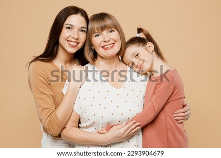 Close up happy smiling women wear casual clothes with child kid girl 6-7 years old. Granny mother daughter posing look camera hug cuddle isolated on plain beige background. Family parent day concept Royalty-Free Stock Photo #2293904679