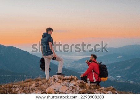 Two friends tourists are relaxing while drinking a cup of coffee during the hiking on the mountain top adventure travel. 