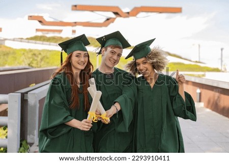Photo of a group of multiracial young people taking selfies with one on graduation day. University campus