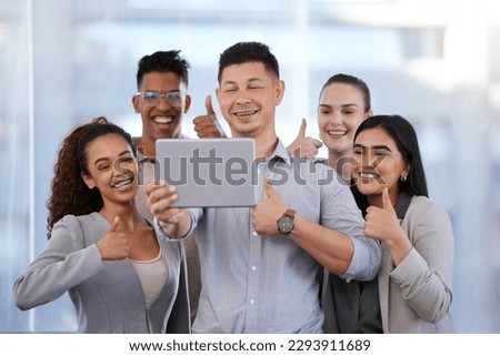 Whats better than one like Try five. Shot of a group of young businesspeople taking selfies with a digital tablet and showing thumbs up in a modern office.