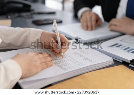 Businesspeople working in the office on official corporate papers, office workers reviewing stack of financial documents and working on business report. Equilibrium