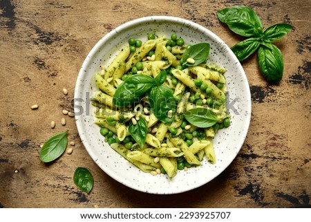 Spring pasta penne with basil pesto and sweet pea in a bowl on a rustic wooden background. Top view with copy space. Royalty-Free Stock Photo #2293925707